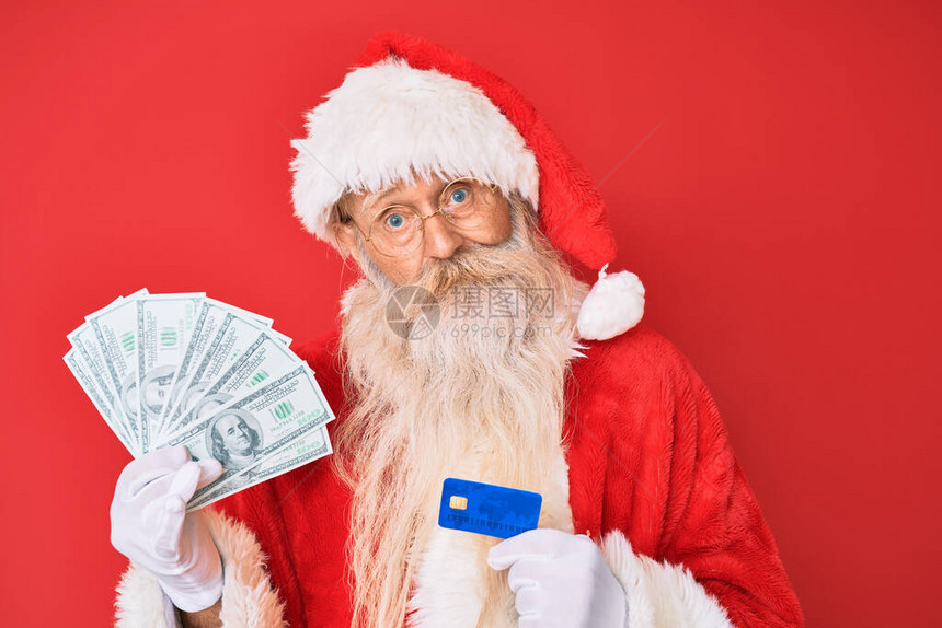 穿着圣达克萨斯服装的老人持有美元和信用卡没有线索和困惑的表情图片