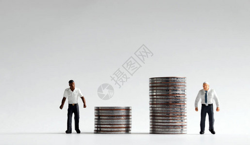 工资歧视的不公平概念站在一堆硬币背景图片