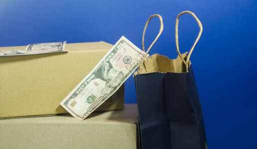 在线购物概念经典蓝背景的纸盒箱和纸袋纸币堆积美元黑色星期五促销售图片
