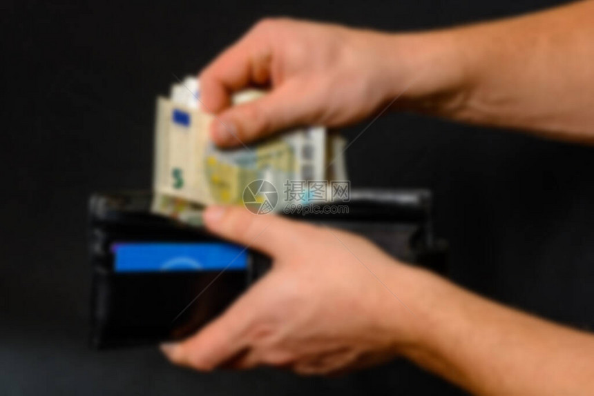 男人从钱包黑背景和黑钱包中抽取钱图片