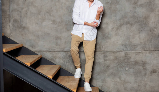 男人穿着白衬衫站在离家墙壁附近的楼梯上背景图片