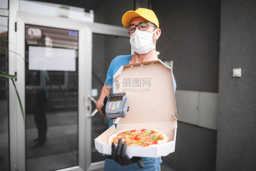 带着防护医用口罩的送货员拿着比萨盒和流行病的日子图片