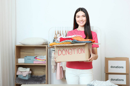 一名年轻女志愿人员为需要室内房间的人募集一箱捐款图片