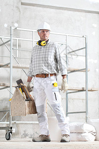 手持工具箱的男建筑工人戴手套安全帽眼镜和听力保护耳机图片
