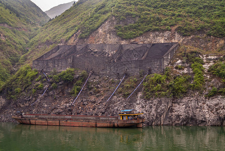 长江巫峡在绿色树叶海岸线上的煤炭装卸码头上方的墙体结构覆盖着山图片