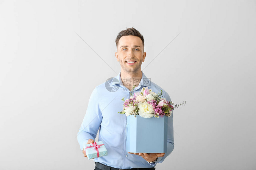 英俊男人盛着一束美丽的鲜花和光图片