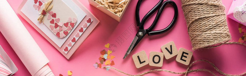 情人节装饰剪刀包装纸麻绳礼品贺卡和在粉红背景的木块上写情图片
