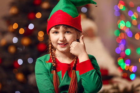穿着精灵装扮的小女孩在圣诞节装饰的房间图片