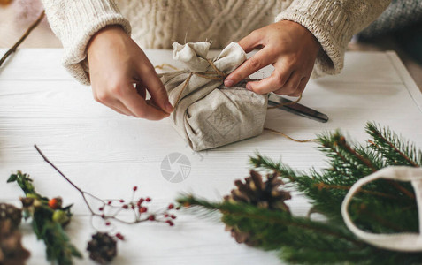 女手用亚麻织物包裹时尚的圣诞礼物背景图片
