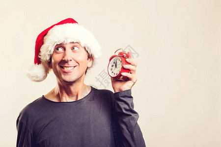 有趣的家伙戴着的帽子男人拿着复古闹钟新年概念已经快十二点了圣诞节时间销售和折扣图片