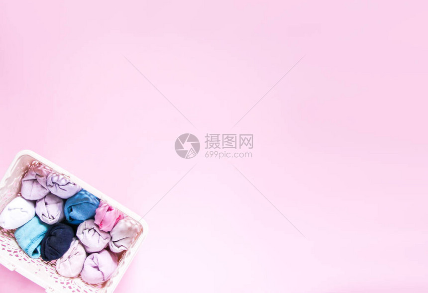 家用衣柜内垂直储存的多彩衣服软粉红色背景的纺织品盒图片