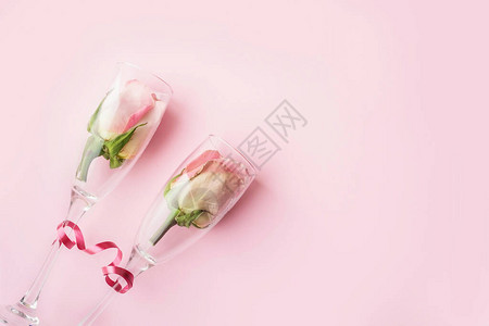 粉红色背景上酒杯中的玫瑰节日生日婚礼情人节妇女节的背景顶视图图片