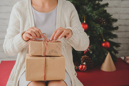 在庆祝之夜整理圣诞礼物时坐在和拿着一堆礼品盒的羊毛大衣上紧贴着无法图片