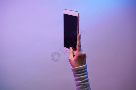 男人手的特写镜头与智能手机和空白的黑色屏幕在空白的紫色背景图片