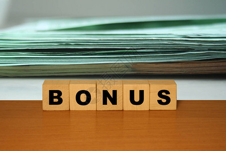 BONUS在用美元或欧元背角方块的立方块上的木桌纸上发来的B图片