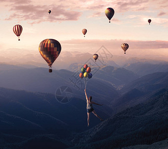 年轻女子从山崖上跳下带着热气球飞翔高清图片
