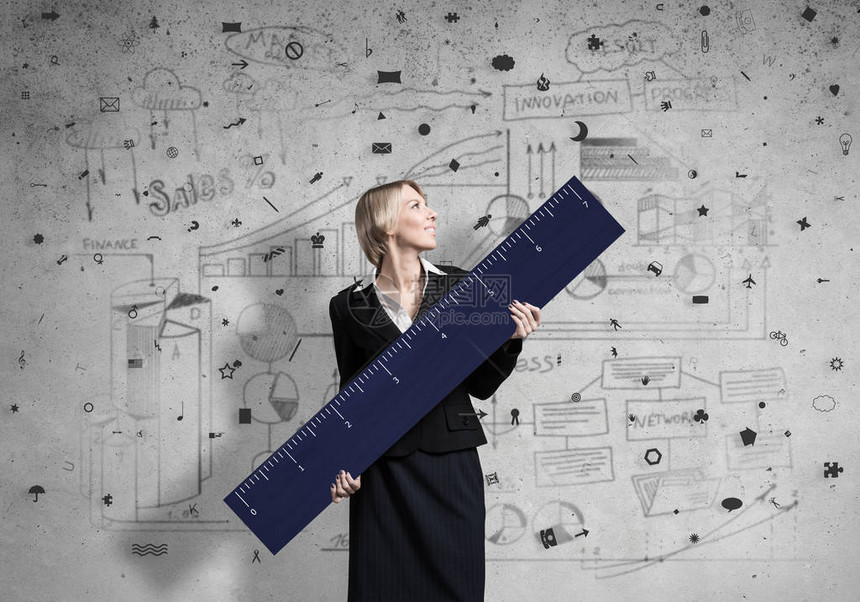 女人在背景黑板上拿着大尺子女商人用尺子测量东西员工招聘和能力评估人力资源招聘创造图片