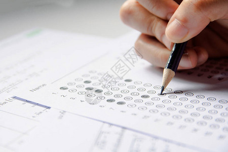 学生手持铅笔在答题纸和数学问题纸上书写选定的选项学生测试做考图片