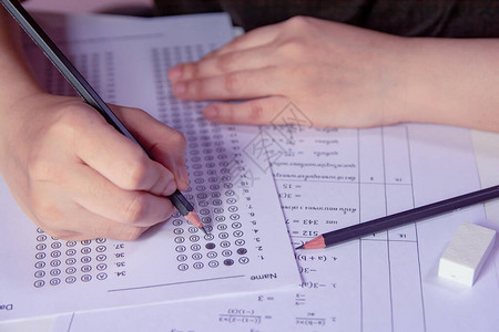 学生手持铅笔在答题纸和数学问题纸上书写选定的选项学生测试做考背景图片