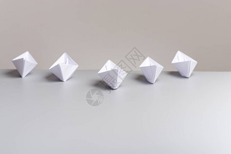五艘白纸船上的白纸船在灰色背景的白桌上图片