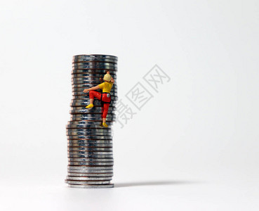 一个迷你女人攀爬着一堆硬币无限竞争社会的概念图片