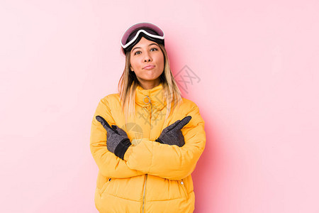 身穿粉红色背景滑雪服的年轻白种女人侧着身子图片