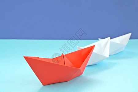 一艘红色的自折叠纸船躺在蓝色的表面上图片