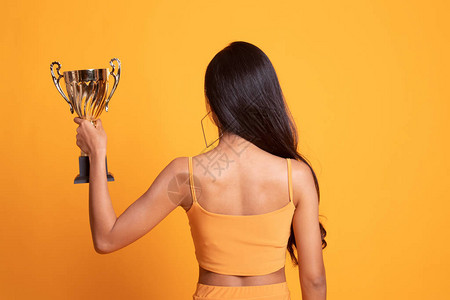 成功年轻亚洲女背影持有黄色奖图片