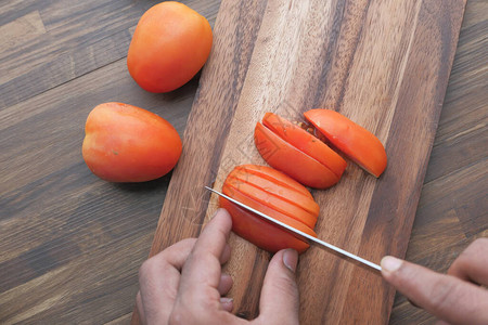 男子在木板上用刀切番茄图片