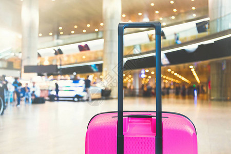 机场候机楼候机区的亮粉色手提箱背景图片