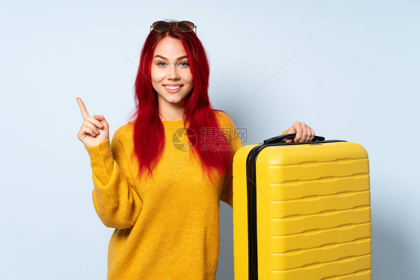 旅行女孩拿着一个手提箱孤立在蓝背景上快图片