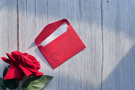 白色桌子上的红色信封和红玫瑰背景图片
