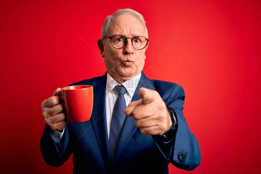 头发灰白的高级商人在红色背景下喝着热咖啡图片