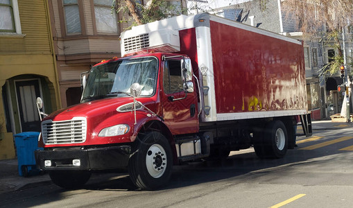 在城市附近停靠的红色冷冻运货卡车的前侧和图片