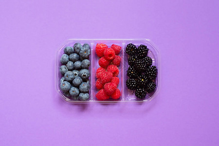 由新鲜蓝莓草莓和黑莓组成的平板组在一个透明的塑料容器中图片