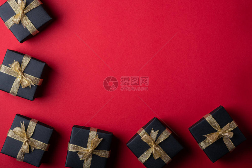 红纸框边背景上带金丝带的黑色礼盒图片