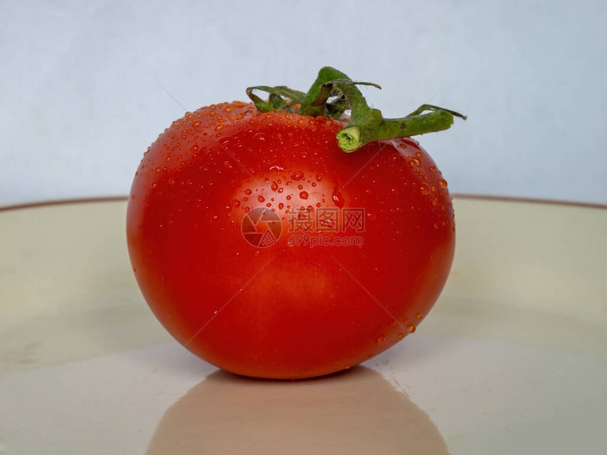从侧面看盘子上有一个新鲜的红番茄图片