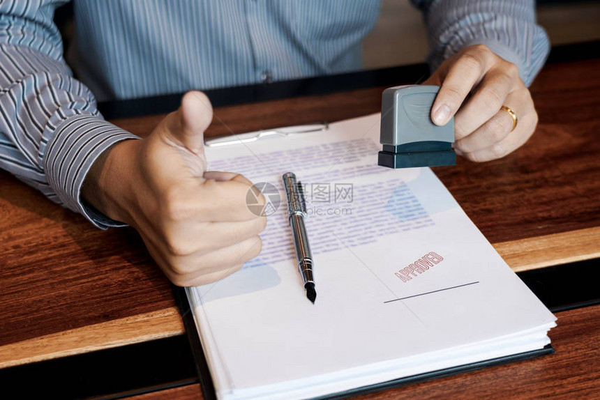 商人手公证人手墨水批准印章在已批准的合同表格文件合同贷款货币概图片