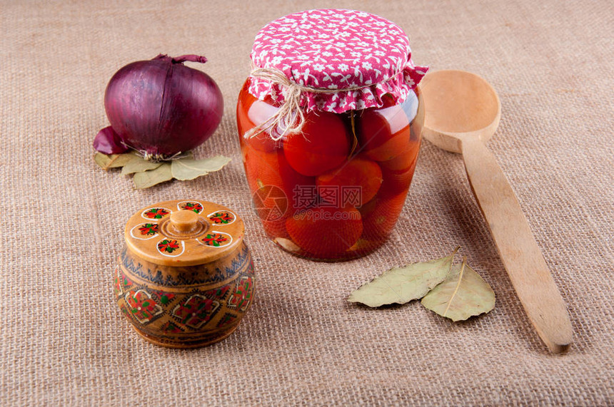 产品和餐具的组成放在麻布上红洋葱月桂叶透明玻璃罐中的西红柿布盖木勺和图片