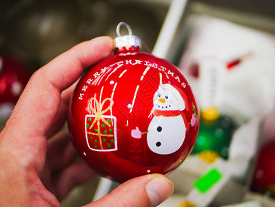 手中的红色圣诞球有铭文和雪人可爱的新年礼物人手拿图片
