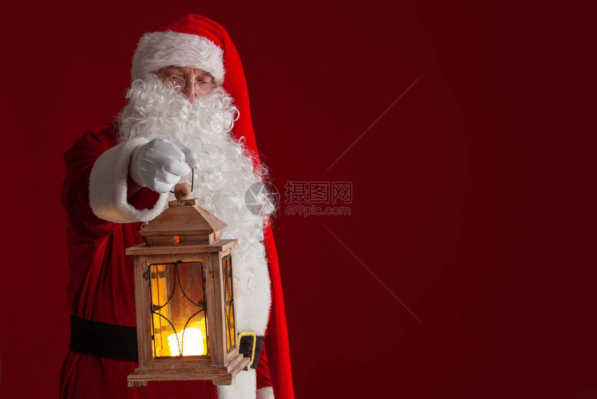 照片显示圣诞老人在黑暗红背景上拿着图片