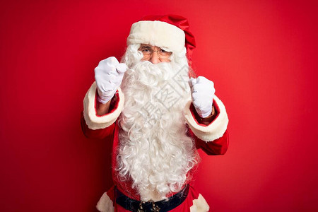 穿着圣诞老人服装的中年英俊男子站在孤立的红色背景上图片