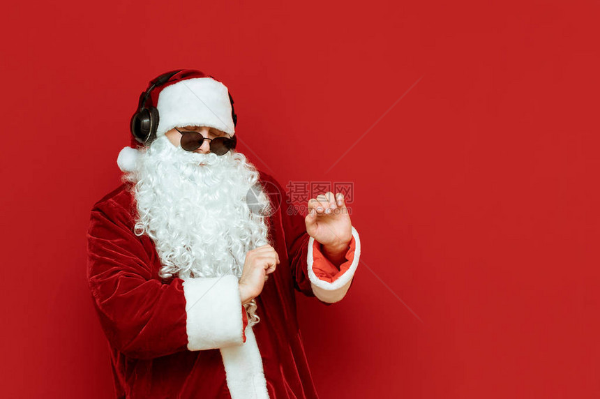 快乐的圣诞老人戴着墨镜在红色背景上跳舞图片