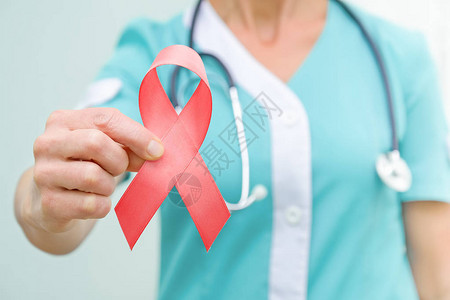 医生手中提高对艾滋疾病认识的红色丝带图片