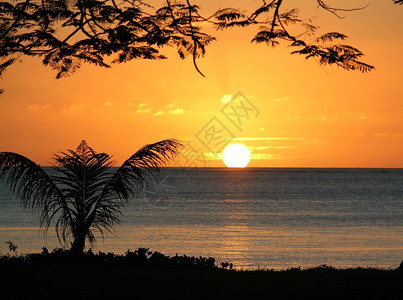 满圆的太阳在海水中落下被海滩上背景图片