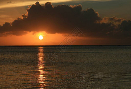 在海中倒映的一轮落日之上的戏剧云彩图片