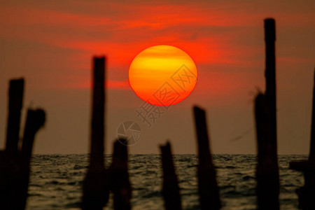太阳正落入大海从大海和橙色天空反射的光破碎的树桩是失焦的泰国攀牙图片