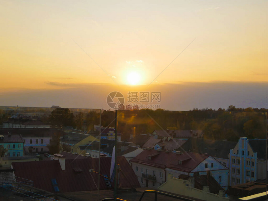 温暖的日落在城市城市上空的日落建筑物的剪影太阳的橙黄色圆盘图片