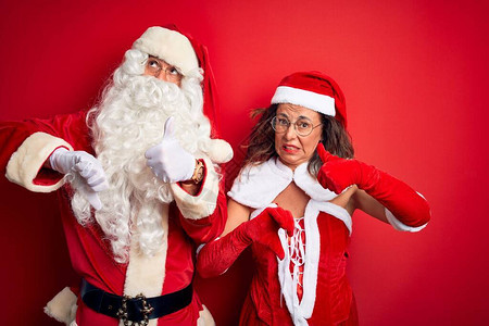 中年夫妇穿着圣诞老人服装和眼镜的中年夫妇在孤立的红色背景之上图片