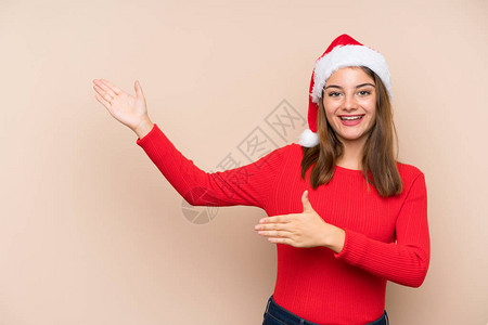带着圣诞帽子的年轻女孩在孤立的与世隔绝的上伸出双手到旁图片
